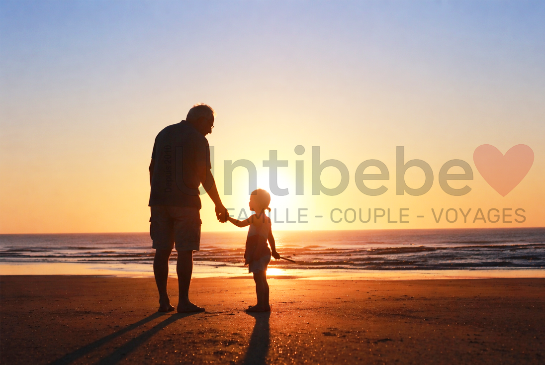 deux générations grand pere enfant devant un coucher de soleil